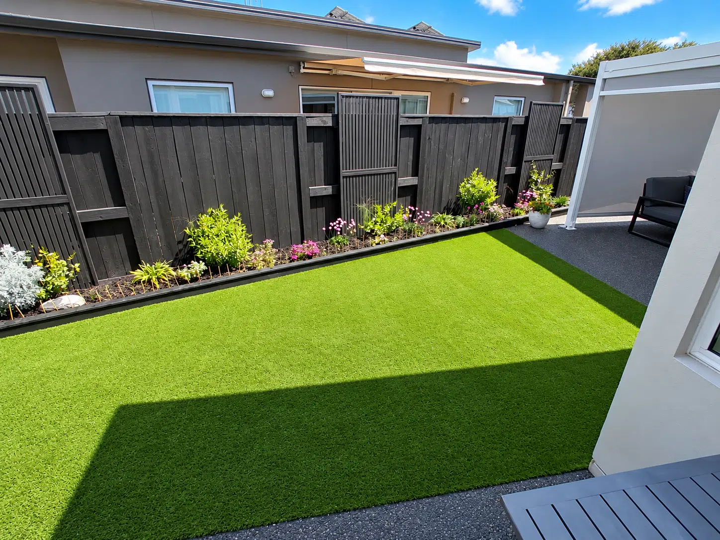 Meadow FlowTech artificial grass installed in a residential Tauranga backyard with garden beds